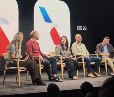 Five panelists seated on stage at an Apple event in front of an iOS 26 branded backdrop with the American Airlines logo