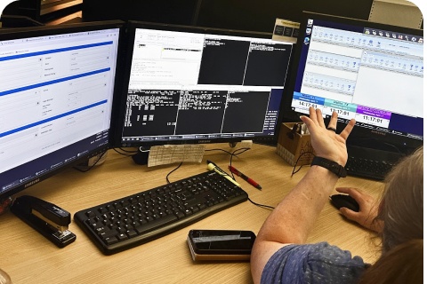 An IOC team member working at a desk with three monitors and a keyboard